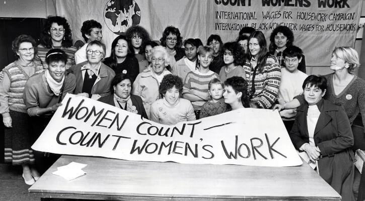 A group of women stand in front of a banner that reads 'women count - count women's work'.