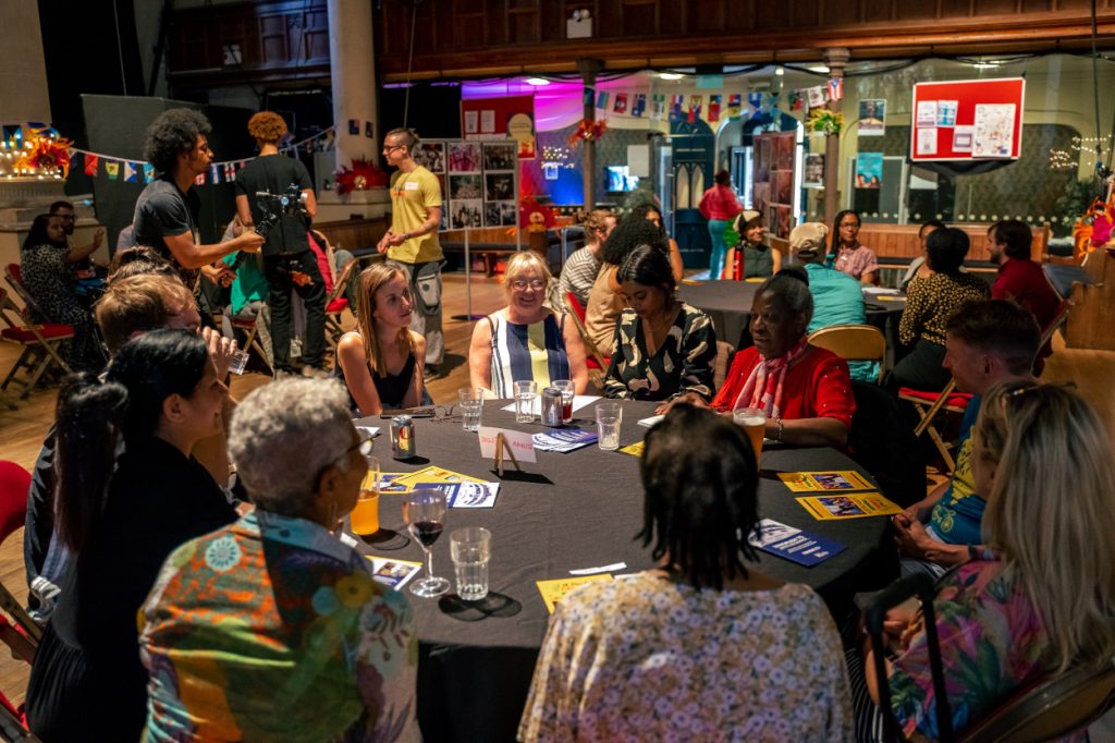 Credit Keyane Allman St Paul's Carnival An image of a group of people sitting around tables in a large hall